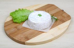 queijo camembert na tábua de madeira e fundo de madeira foto