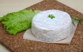 queijo camembert na tábua de madeira e fundo de madeira foto