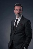 retrato de um elegante elegante empresário sênior com barba e roupas de negócios casuais em estúdio fotográfico isolado em fundo escuro, gesticulando com as mãos foto