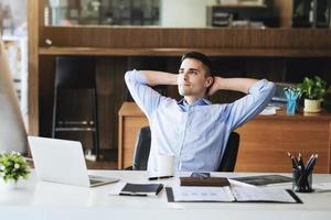 gerente de marketing masculino descansando e sorrindo enquanto trabalha para reduzir a sonolência antes de usar computadores, ipads e materiais de marketing. foto