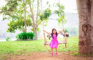 jovem menina asiática em balanço de árvore foto