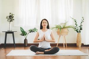 mulher asiática fazendo yoga meditação em casa