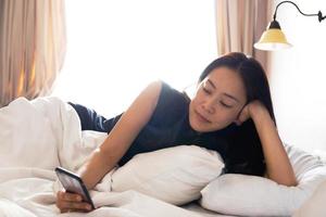 mulher relaxante com telefone na cama foto