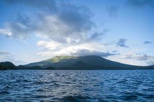 oceano perto da montanha com nuvens foto