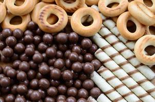 muitos túbulos doces crocantes, bolas de chocolate derretidas e bagels amarelos estão em uma superfície de madeira. vista de perto foto