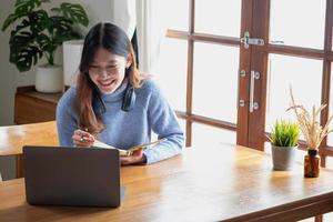 relaxe, desestresse, relaxe, divirta-se. mulheres asiáticas fazem anotações de seu passado e gravam videoclipes em seus laptops em casa. foto