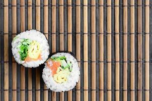 rolos de sushi encontra-se em uma esteira de serragem de palha de bambu. comida asiática tradicional. vista do topo. minimalismo plano leigo com espaço de cópia foto