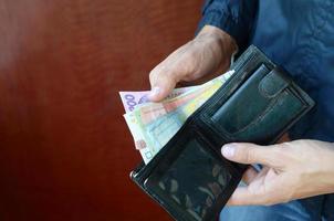 fechar as mãos masculinas abriu a carteira ou bolsa com moeda ucraniana hryvnia foto