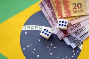cubos de dados com notas de dinheiro brasileiro na bandeira da república do brasil. conceito de sorte e jogos de azar no brasil foto