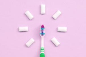 escova de dentes e gomas de mascar estão em um fundo rosa pastel foto