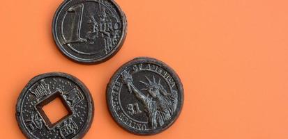 três produtos de chocolate na forma de moedas de euro, eua e japão encontram-se em um fundo de plástico laranja. um modelo de moedas de dinheiro em forma comestível foto