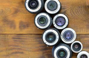 várias lentes fotográficas estão em um fundo de madeira marrom. espaço para texto foto