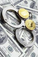 algemas da polícia e bitcoins estão em um grande número de notas de dólar. o conceito de problemas com a lei durante as operações ilegais de mineração de criptomoedas e bitcoin foto