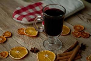 fatias de laranja secas e vinho quente na mesa foto