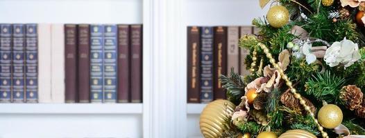 uma linda árvore de natal decorada no fundo de uma estante com muitos livros de cores diferentes. imagem de fundo de natal da biblioteca foto