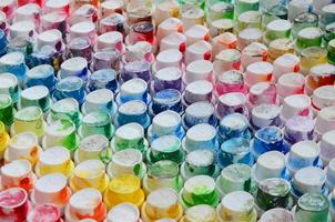 um padrão de muitos bicos de um pulverizador de tinta para desenhar grafite, manchado em cores diferentes. as tampas de plástico são dispostas em muitas fileiras formando a cor do arco-íris foto