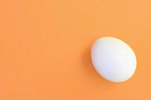 um ovo de páscoa branco em um fundo laranja brilhante foto