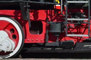 rodas da velha locomotiva a vapor preta dos tempos soviéticos. o lado da locomotiva com elementos da tecnologia rotativa de trens antigos foto