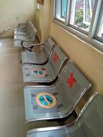 cadeiras de ferro, no saguão do hospital. os assentos são afixados com adesivos informativos para manter a distância e prevenir o contágio do covid-19. foto