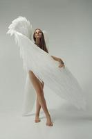 uma garota anjo romântico em uma roupa branca com asas brancas foto