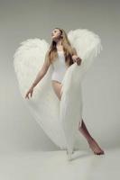 uma garota anjo romântico em uma roupa branca com asas brancas foto