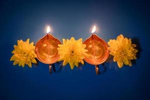 feliz Diwali. lâmpadas de óleo diya e flores amarelas sobre fundo azul. celebrando o tradicional feriado indiano de luz. foto