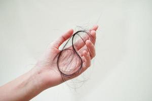 mulher asiática tem problema com perda de cabelo comprido anexado na mão. foto