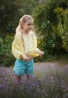 linda garotinha em um campo com lavanda. foto