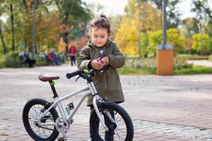 linda garota tocando campainha de bicicleta no parque. foto