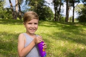 retrato de criança bonita com garrafa de água no parque. foto