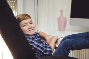 menino feliz relaxante com os pés na mesa em casa. foto