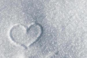 fundo de inverno de cristais de neve cintilantes ao sol. símbolo do coração do amor foto