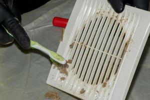 limpar um exaustor de cozinha muito sujo da sujeira com uma escova. um homem limpa as partes de um ventilador com uma escova foto