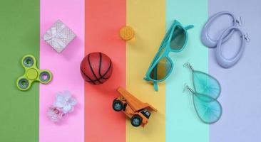 composição na moda com brincos, óculos de sol, lata de bebida, bola de basquete, caminhão de brinquedo, caixa de presente, flor e girador foto