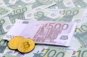 bitcoins físicos dourados estão em um conjunto de denominações monetárias verdes de 100 euros. muito dinheiro forma uma pilha infinita foto