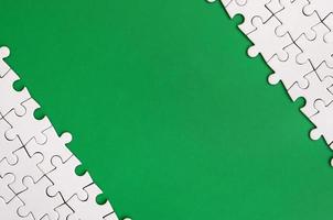 fragmento de um quebra-cabeça branco dobrado no fundo de uma superfície de plástico verde. foto de textura com espaço de cópia para texto