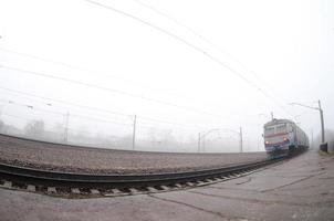 o trem suburbano ucraniano corre ao longo da ferrovia em uma manhã nublada. foto olho de peixe com distorção aumentada