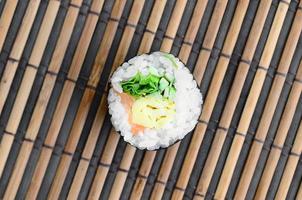 rolo de sushi deitada em uma esteira de serragem de palha de bambu. comida asiática tradicional. vista do topo. minimalismo plano leigo com espaço de cópia foto