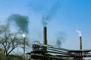fumaça da chaminé de uma fábrica de produtos químicos contra o céu azul. o problema da poluição ambiental. conceito de ecologia foto