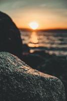 close up da rocha perto da água ao pôr do sol foto