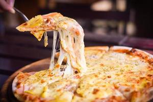 pizza de queijo havaiano na mesa de madeira. conceito de comida caseira foto