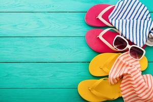 chinelos rosa, toalha, óculos de sol e espaço de cópia sobre fundo azul de madeira. vista do topo. conceito de férias de verão na praia. foto