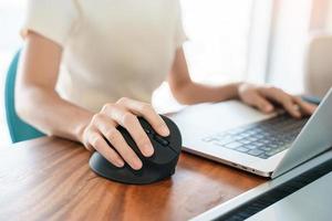 mão de mulher usando mouse ergonômico de computador, prevenção de dor no pulso porque trabalha muito tempo. tenossinovite de Quervain, sintoma de interseção, síndrome do túnel do carpo ou conceito de síndrome do escritório foto