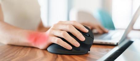 mão de mulher usando mouse ergonômico de computador, prevenção de dor no pulso porque trabalha muito tempo. tenossinovite de Quervain, sintoma de interseção, síndrome do túnel do carpo ou conceito de síndrome do escritório foto