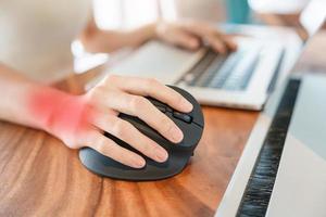 mão de mulher usando mouse ergonômico de computador, prevenção de dor no pulso porque trabalha muito tempo. tenossinovite de Quervain, sintoma de interseção, síndrome do túnel do carpo ou conceito de síndrome do escritório foto