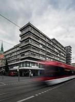 moderno edifício de vidro alto na elegante área da vila de tecnologia da embaixada, trabalhadores carregando caixote de lixo caminhando em direção ao prédio foto