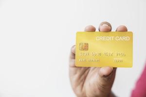 mão de close-up de homem asiático segurando o cartão de crédito de ouro amarelo na mão. isolado no fundo branco. conceito de finanças, negociação, comunicação, social, tecnologia, negócios foto