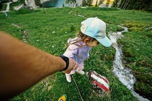 pai segura a mão da filha perto da fonte de água limpa da montanha em vorderer gosausee, gosau, alta áustria. foto