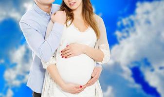 retrato de jovem casal aguardando o garoto isolado em fundo azul, jovem casal atraente mãe grávida e pai feliz, lindo casal jovem esperando bebê foto