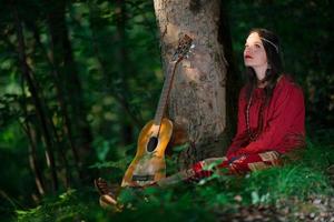 garota hippie com a guitarra na floresta foto